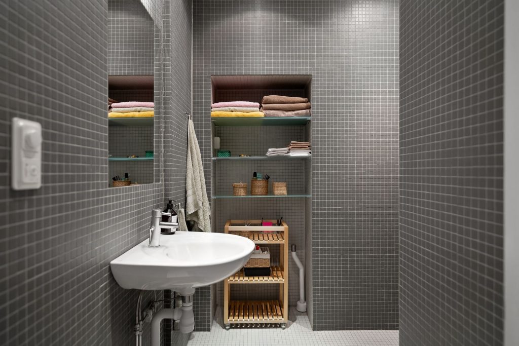 Étagères murales de rangement dans une petite salle de bain lumineuse