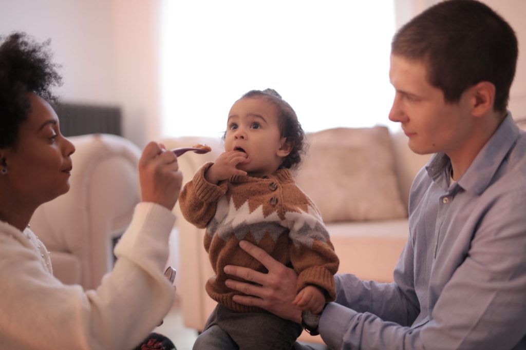 Parent donnant la cuillère à un bébé pendant un repas de diversification alimentaire