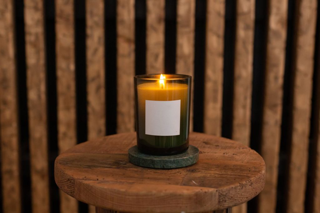 Bougie allumée dans un photophore en verre posée sur une table à bonne distance des objets inflammables