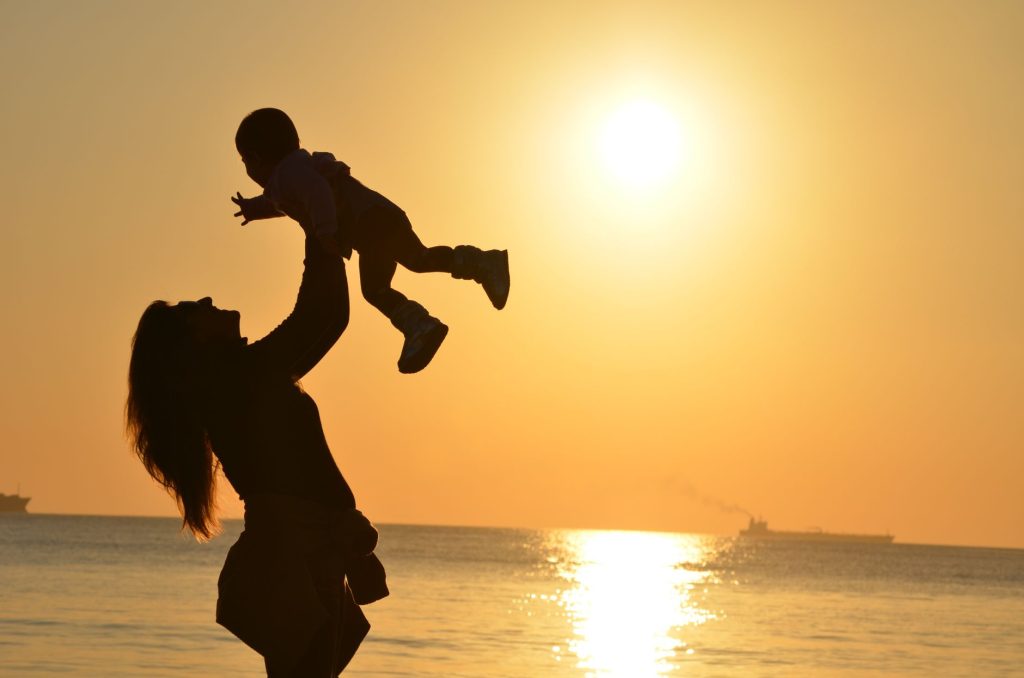 Maman et enfant complices au coucher du soleil, moment de tendresse